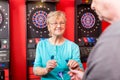 Mature woman holding dartboard arrows Royalty Free Stock Photo