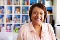 Portrait Of Smiling Mature Woman In Home Office By Bookcase