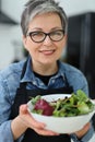 Portrait of a smiling mature woman with a plate of fresh salad for lunch Royalty Free Stock Photo