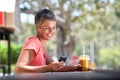 Smiling middle age woman sitting outside with mobile phone and drink Royalty Free Stock Photo