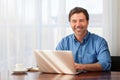 A portrait of a smiling middle-aged bearded man on a window background