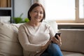 Portrait of smiling middle aged lady resting on sofa. Royalty Free Stock Photo