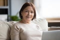 Portrait smiling middle aged woman sitting on couch with laptop. Royalty Free Stock Photo