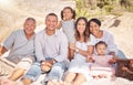 Portrait of a smiling mixed race family with little girls sitting together at the beach. Adorable little kids bonding Royalty Free Stock Photo