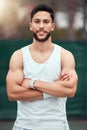 Portrait of smiling mixed race tennis player with arms folded and standing alone on court. Fit confident hispanic sports Royalty Free Stock Photo
