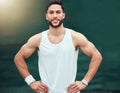 Portrait of smiling mixed race tennis player standing alone on a court. Fit hispanic sports professional with hands on Royalty Free Stock Photo