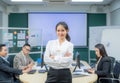 Portrait smiling modern business woman standing in an office at team meeting. Confident young Asian businesswoman with colleagues Royalty Free Stock Photo