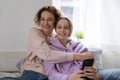 Portrait of smiling mom and teen daughter relax at home