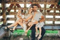 Portrait of a smiling mother and father sitting on a bench outside with their young daughters in gazebo in park Royalty Free Stock Photo