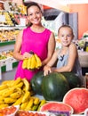 mother with girl picking bananas on market . Royalty Free Stock Photo