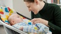 Portrait of smiling mother looking at her cute baby son sitting in electric rocking chair. Child development and happy Royalty Free Stock Photo