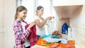 Portrait of smiling young mother with teenage daughter folding clothes after laundry