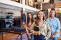 Portrait Of Smiling Multi-Cultural Female Sales Team In Fashion Store In Front Of Clothing Display