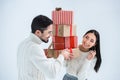 portrait of smiling multicultural couple looking at each other while holding stack of wrapped christmas gifts