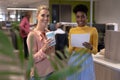 Portrait of smiling multiracial businesswomen with document and drink at modern workplace