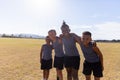 Portrait of smiling multiracial elementary boys standing with arm around on school soccer field