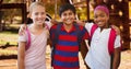 Portrait of smiling multiracial girls and boy with arm around standing at park Royalty Free Stock Photo