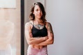 Portrait of smiling muscular caucasian woman standing with arms crossed by window at gym. Sport and healthy lifestyle Royalty Free Stock Photo