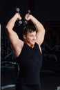 Portrait of a smiling muscular young man lifting weights on gym background,friendly Royalty Free Stock Photo