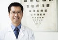 Portrait of smiling optometrist with an eye chart in the background Royalty Free Stock Photo