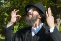 Portrait of smiling orthodox Jewish man holding long Sidelocks, Peyot, Payot