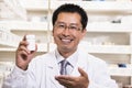 Portrait of smiling pharmacist holding a prescription medication bottle in his hand
