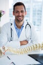 Portrait of smiling physiotherapist sitting with spine model