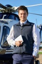 Portrait Of Smiling Pilot Standing In Front Of Helicopter With D