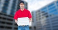 Portrait of smiling pizza delivery man holding pizza box against buildings Royalty Free Stock Photo