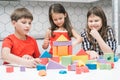 Portrait of smiling preteen children friends play building tower house castle of construction blocks geometric figures. Royalty Free Stock Photo
