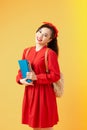 Portrait of a smiling pretty asian girl holding books and looking at camera isolated over orange background Royalty Free Stock Photo