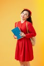 Portrait of a smiling pretty asian girl holding books and looking at camera isolated over orange background Royalty Free Stock Photo