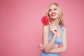 Portrait of a smiling pretty blonde woman in swimsuit posing with heart shaped lollipop and looking away Royalty Free Stock Photo