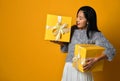 Portrait of a smiling pretty girl holding two gift boxes isolated over yellow background Royalty Free Stock Photo