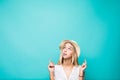 Portrait of a smiling pretty summer girl in straw hat pointing two fingers up at copyspace isolated over blue background Royalty Free Stock Photo