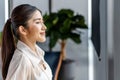 Portrait of smiling pretty young business woman standing on workplace office and looking out to window.Smile and Thinking Royalty Free Stock Photo