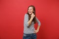 Portrait of smiling pretty young woman in casual striped clothes standing and looking aside isolated on bright red wall Royalty Free Stock Photo