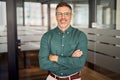 Portrait of smiling professional mature business man standing in office.