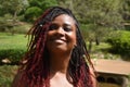 A portrait of a smiling radiant and spectacular woman of color with a rare, braided hair style of red dye at the ends