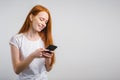 Portrait of a smiling redhead woman holding smartphone and texting Royalty Free Stock Photo