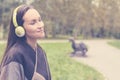 Young happy woman listening music from smartphone with headphones in a quiet Park Royalty Free Stock Photo