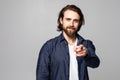 Portrait of a smiling satisfied man pointing at camera isolated on a gray background Royalty Free Stock Photo