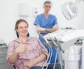 Portrait of smiling satisfied woman visiting dentist giving thumbs up in the dental clinic