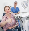Portrait of smiling satisfied woman visiting dentist giving thumbs up in the dental clinic Royalty Free Stock Photo