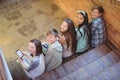 Portrait of smiling school friends sitting on staircase using mobile phone Royalty Free Stock Photo