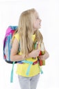 Portrait of smiling school girl child with backpack, holding crayons and books looking up on side at copy space.