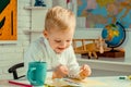 Portrait of smiling schoolboy doing his homework in classroom at school, Kid gets ready for school. Royalty Free Stock Photo