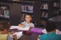 Portrait of smiling schoolboy doing his homework in library Royalty Free Stock Photo