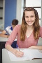 Portrait of smiling schoolgirl doing homework in classroom Royalty Free Stock Photo