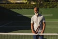 Portrait of smiling senior african american man holding tennis racket on tennis court Royalty Free Stock Photo